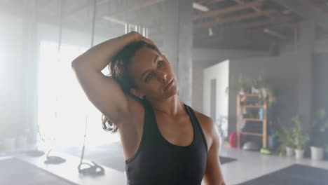 stretching arm, woman in gym wearing fitness attire, focusing on workout