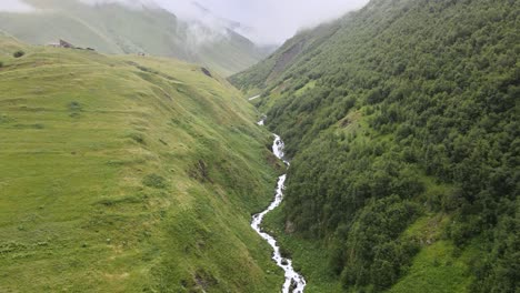 Aerial-shot-of-river-surrounded-by-mountains-and-fog