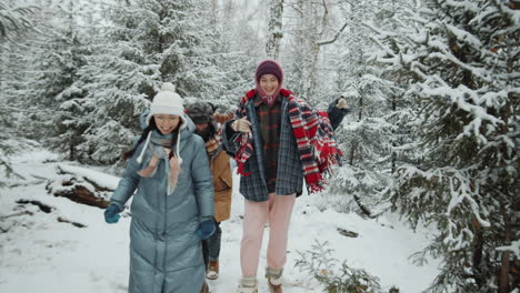 happy friends running in snowy forest on winter day