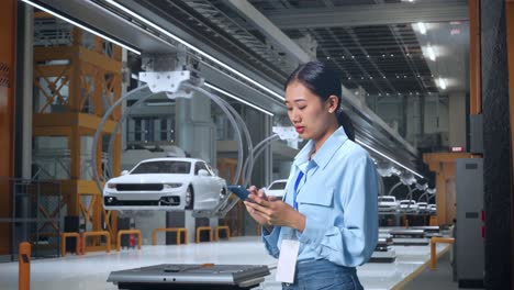 mujer usando el teléfono en una fábrica de automóviles