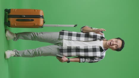 full body of asian male traveler with luggage and passport smiling and saying wow while standing in the green screen background studio