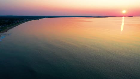 aerial drone view of colorful ocean sunrise in saco, maine with bright colors reflecting off calm rippling sea waves along the new england atlantic coastline