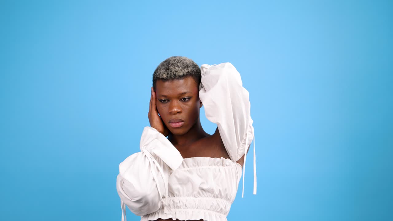 Persona sicura di sé che posa in crop top bianco su sfondo blu