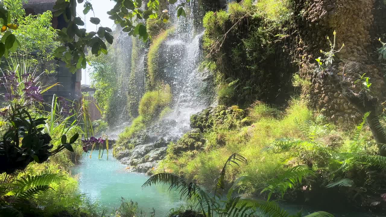Air terjun buatan yang sempurna dengan air pirus di tengah latar hijau yang subur