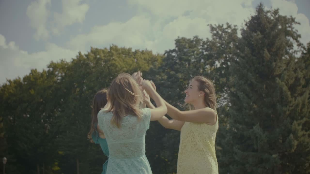 쾌활 한 여자 친구 들 이 야외 에서 원 으로 춤추고 있다