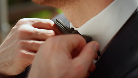 unrecognizable man preparing for wedding outdoors. gentleman standing in park.