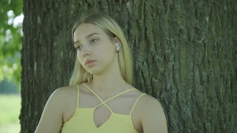 mujer con vestido amarillo bailando junto al árbol en el parque de verano