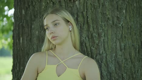 woman in yellow dress dancing by tree in summer park