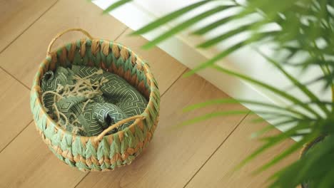 Woven Basket with Green Patterned Textile on Wooden Floor