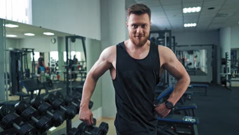 bodybuilder showing his muscular body. bearded athletic man prouds by himself and posing to camera on the fitness center background.