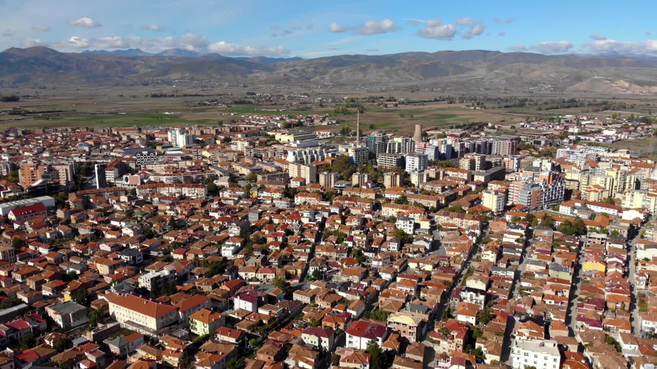 área suburbana de la ciudad de korca en albania con techos rojos y edificios rodeados de montañas