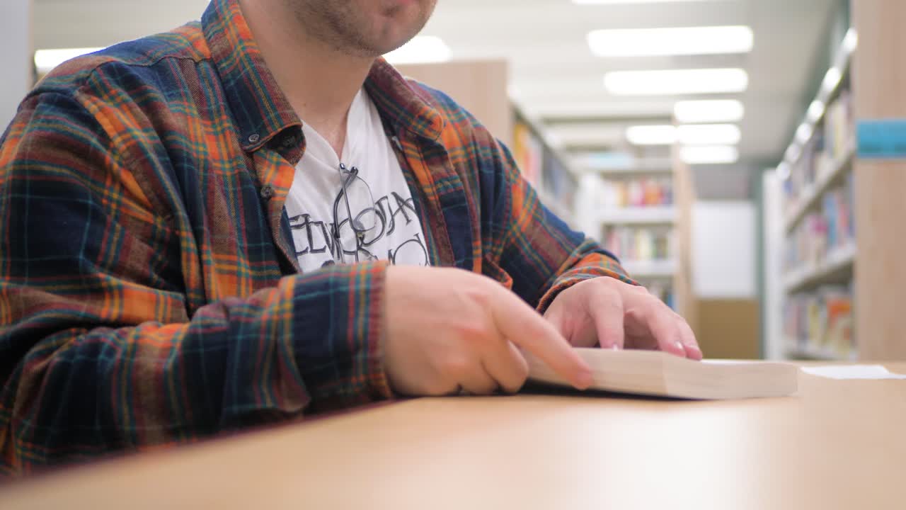 Uomo in flanella che sfoglia un libro in biblioteca