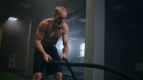 male athlete working out with ropes in old building. athlete man in training with ropes near mirror. battle rope