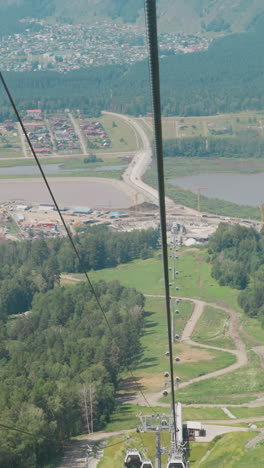 highland landscape with green valley and small town at mountain foot and blurry view of smiling lady riding cable way on summer day slow motion