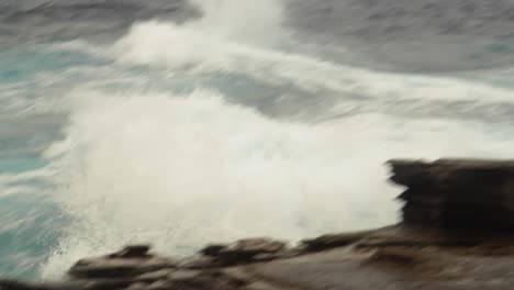 Rough-ocean-waves-churn-and-crash-against-rocks,-panning-medium-shot