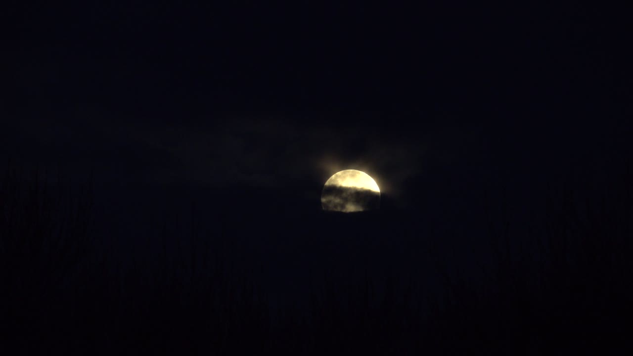 Lua cheia desaparecendo atrás de nuvens em movimento em um céu noturno escuro