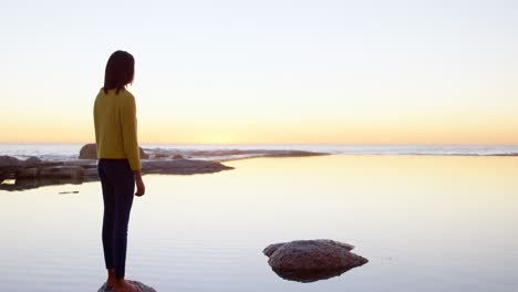 side view of woman standing on rocky shore 4k