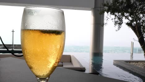 a glass of beer near a poolside view