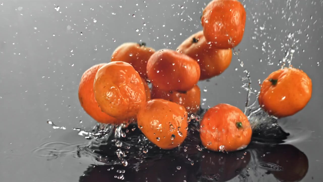 Friske mandariner falder og plasker i vand i slowmotion