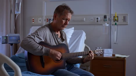 man playing guitar in a hospital bed