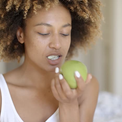 woman sitting on bed and eating apple