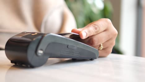 a hand making a contactless payment with a credit card at a pos terminal