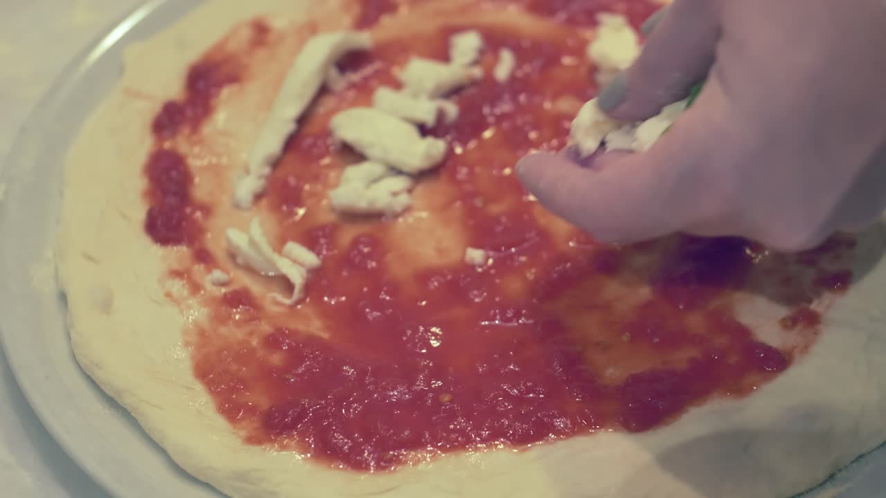 Lady preparing a Margherita Pizza with fresh mozzarella cheese tomato sauce and basil