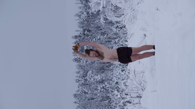 Un uomo si sta riscaldando prima di tentare una verticale nella neve alta - Scatto verticale.