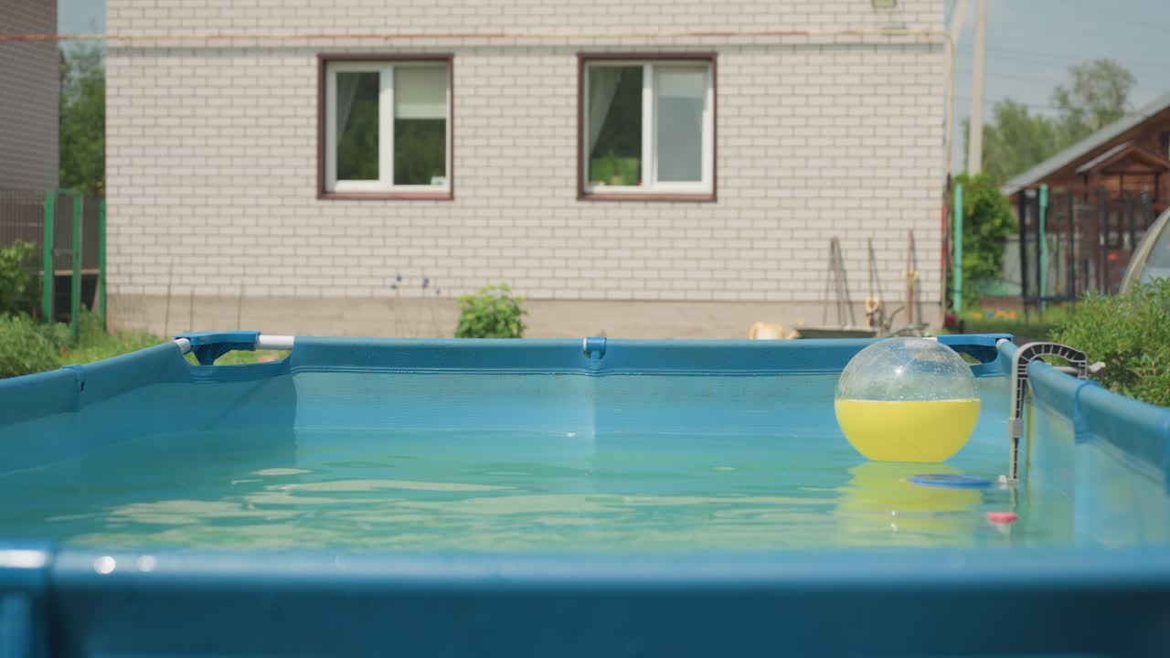 Serene Poolside Summer Setting, Quiet Garden Scene Featuring Floating Yellow Beach Ball And Tranquil Water, Peaceful Summer Environment With Floating Yellow Beach Ball In Silent Backyard Pool
