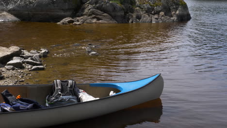 Canoa-Estacionada-En-El-Borde-Del-Agua-Con-Mochilas-En-Ella