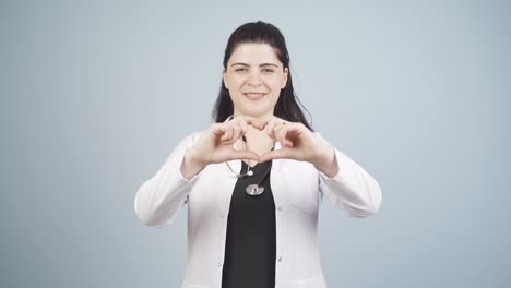 el médico hace el corazón mirando a la cámara.