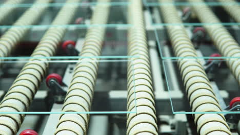 sheets of transparent glass line up on stationary roller conveyor belt