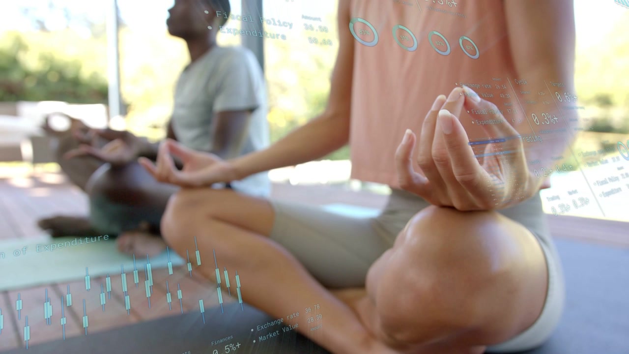 Pair sitting cross-legged on deck, holding mudra, camera revealing charts visualizing health data
