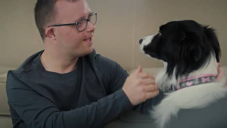 caucasian man with down syndrome sitting on floor and playing with pet dog