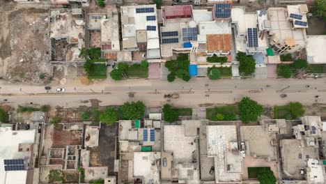 Toma-Aérea-De-Arriba-Hacia-Abajo-De-Una-Calle-En-Mirpur-Khas,-Sindh,-Bordeada-De-Edificios.