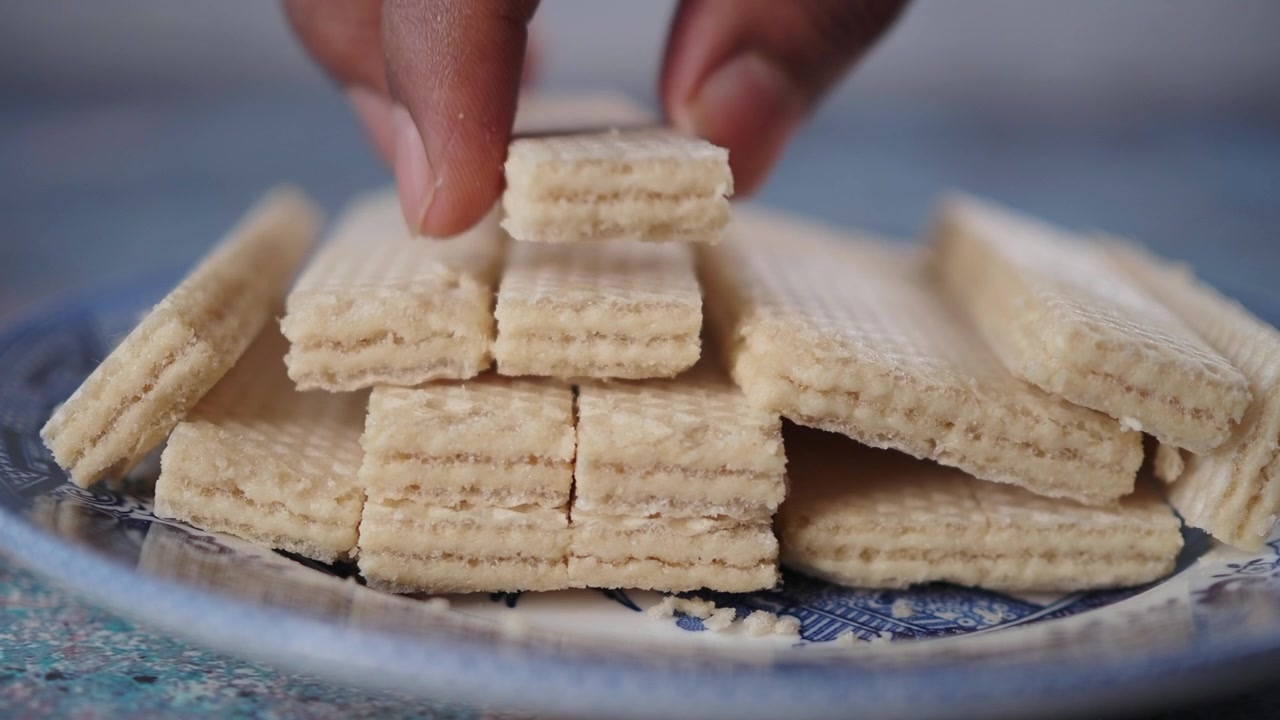 Mano che prende un biscotto wafer croccante da un piatto