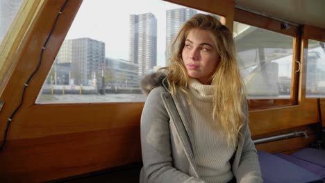 mujer joven con estilo montando un taxi acuático, perdida en sus pensamientos