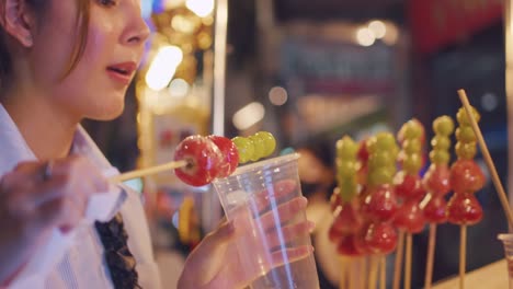 disfrutando de frutas confitadas en un mercado nocturno