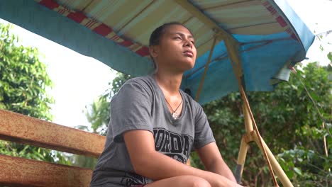 lonely and sad filipina orphan girl sitting on a resting area alone at the orphanage home in the philippines- close up