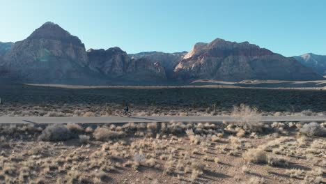 Aerial-drone-shot-of-Red-Rock-Scenic-Highway-with-mountains-in-the-background