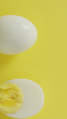 video of overhead view of hard boiled egg half and egg on yellow background