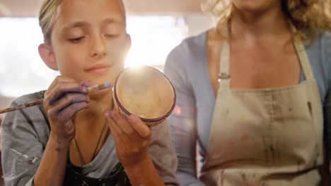 Mother-assisting-her-daughter-in-painting-a-bowl