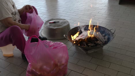 medium shot, put joss paper into the flame