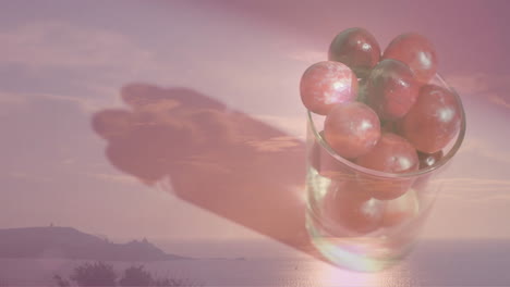 composition of glass of red grapes over landscape background