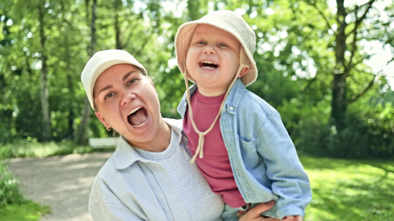 Glad mor med lille søn leger og løber i bypark. Mor og søn på gåtur i den friske luft. Konceptet om et lykkeligt forhold mellem mor og søn. Børneudvikling. Glad tumling