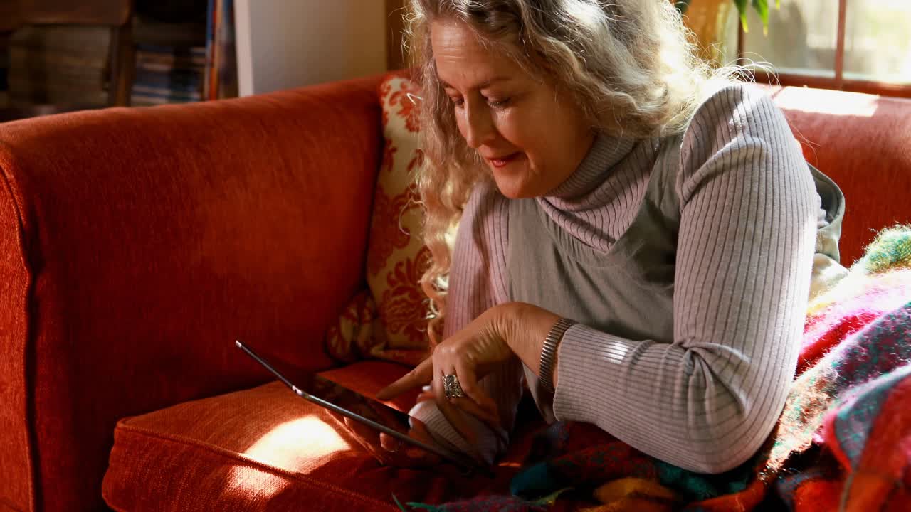거실 4k에서 디지털 태블릿을 사용하는 성숙한 여성