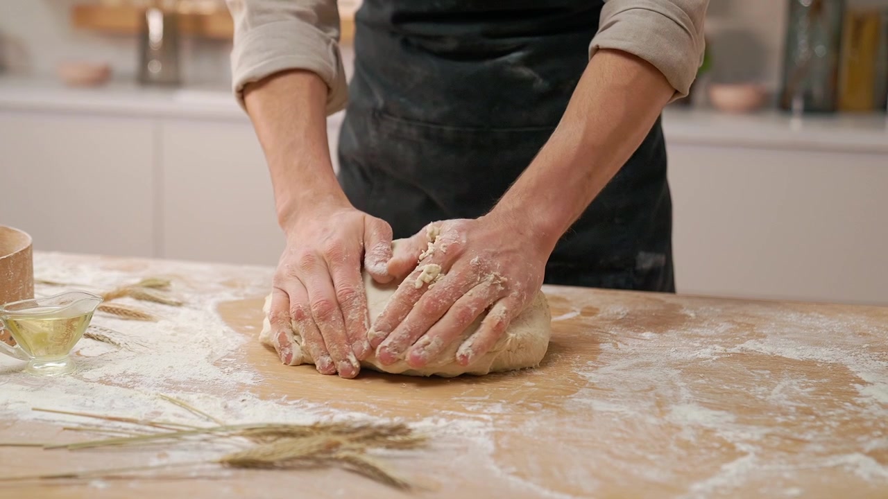 Primo piano delle mani di un fornaio che impastano in cucina