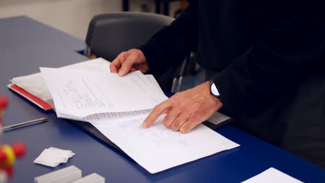 un profesor universitario de ciencias calificando un examen parcial de sus alumnos y tomando notas en una carpeta durante un semestre