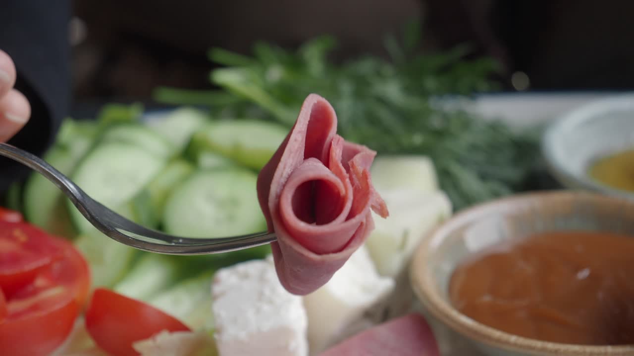 A plate of breakfast with salami, cheese, cucumbers and tomatoes