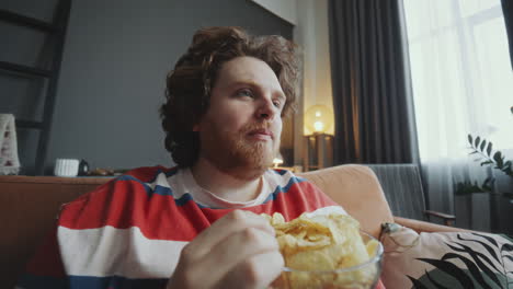 man eating chips while watching tv